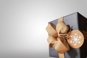 A grey gift box tied with a golden ribbon