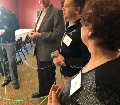 Board members create a web with brightly colored yarn